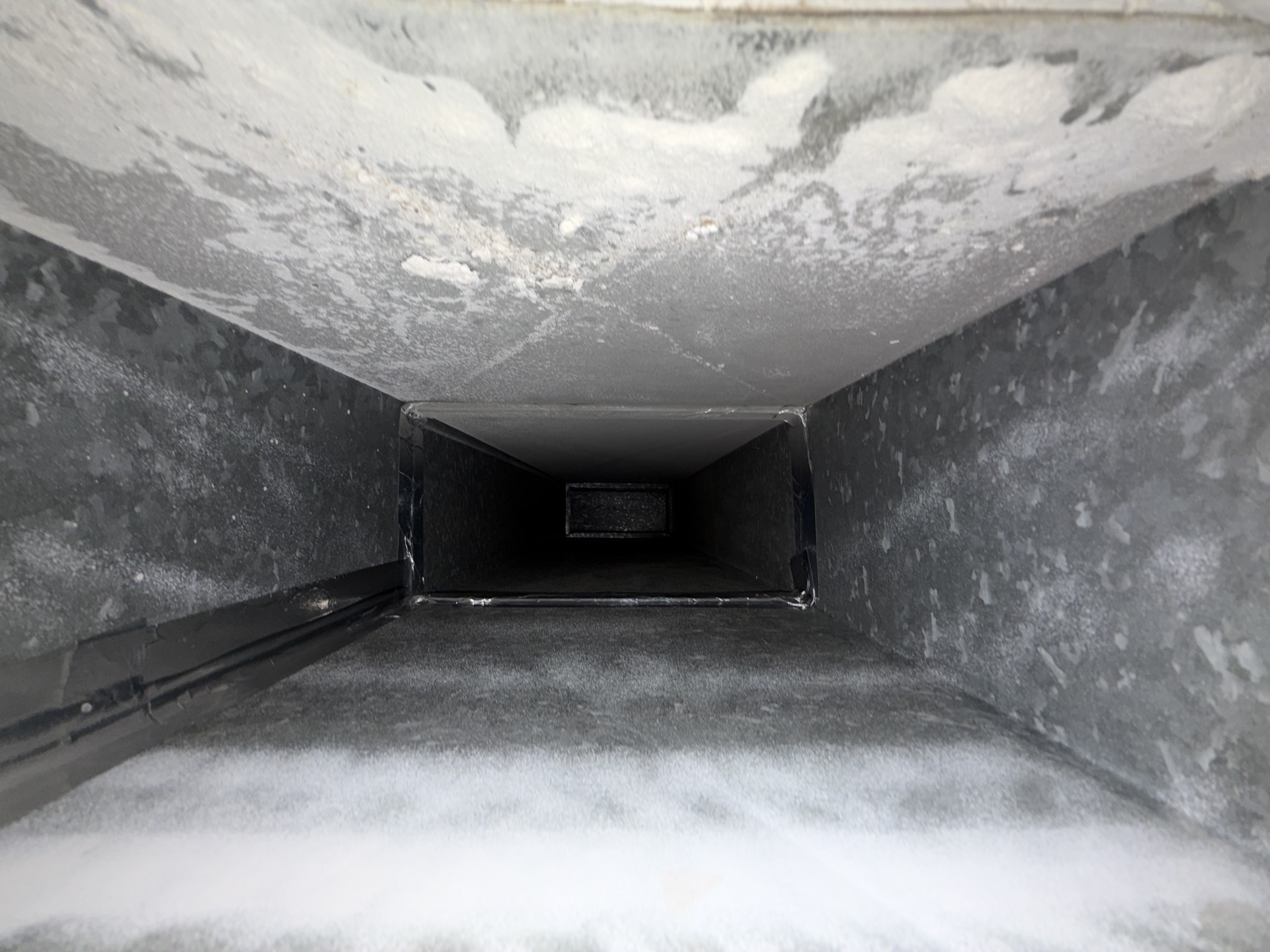 Inside view of a dirty HVAC air duct with heavy dust buildup